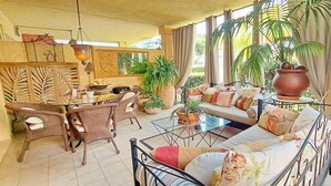 Un espace intérieur accueillant, avec un canapé, des fauteuils, une table à manger et diverses plantes en pot.