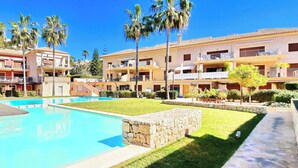 Un complexe hôtelier doté d’une piscine, de plusieurs balcons et de palmiers.