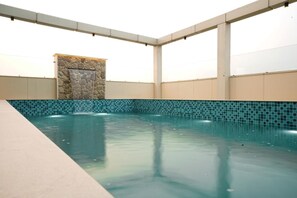 Une piscine intérieure avec un mur en pierre et un sol carrelé.