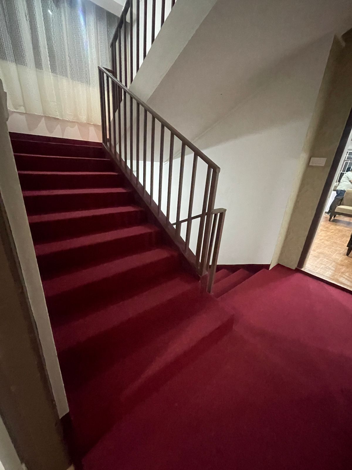 Una escalera con alfombra roja y barandilla de metal.