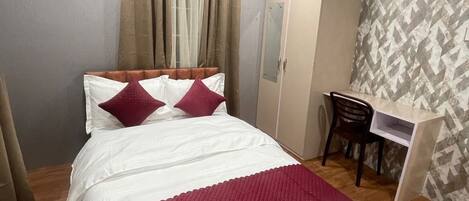 A bedroom with a bed, a desk, and a chair.