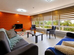 A modern living room with a sofa, armchairs, a coffee table, and a TV.