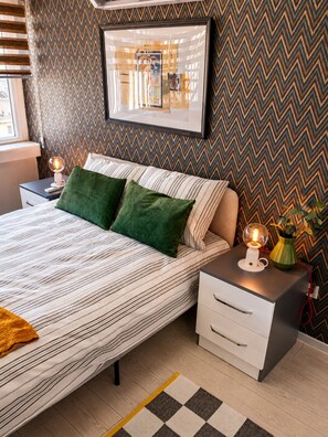 A neatly arranged bedroom with a bed, bedside tables, a lamp, and a framed picture on the wall. - Maxihomes Hadrian Olive (Antalya)