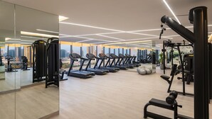 Een moderne sportschool met loopbanden, krachtapparaten en een grote spiegel.