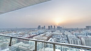 Uitzicht op een stadslandschap vanuit een hoog gebouw, met een heldere lucht en een ondergaande zon in de verte.