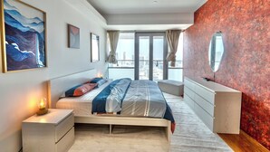 Een moderne slaapkamer met een groot bed, nachtkastjes, een kast en uitzicht op de stad.