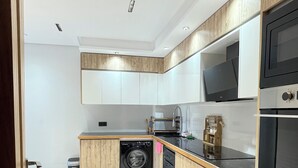 Une cuisine moderne avec des meubles en bois, un lave-linge encastré et un four en acier inoxydable.