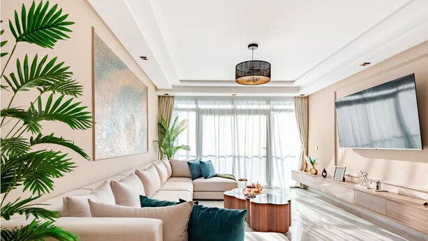 Un salon moderne avec un canapé beige, une table basse et un téléviseur fixé au mur.