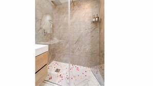 Une salle de bain moderne avec une douche à parois de verre, des murs en marbre et un meuble-lavabo en bois.
