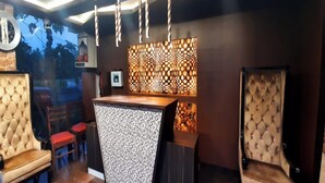 A reception area with a patterned counter, red chairs, and a tufted armchair. - All Season Residency (Port Blair)