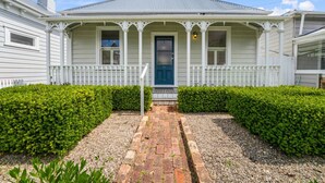 A two-story house with a porch, a blue door, and a gravel pathway. - Best of Both Worlds` Gorgeous Villa near Beaches (Auckland North Shore)