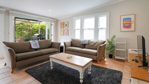 A living room with two sofas, a coffee table, and a TV stand. - Best of Both Worlds` Gorgeous Villa near Beaches (Auckland North Shore)