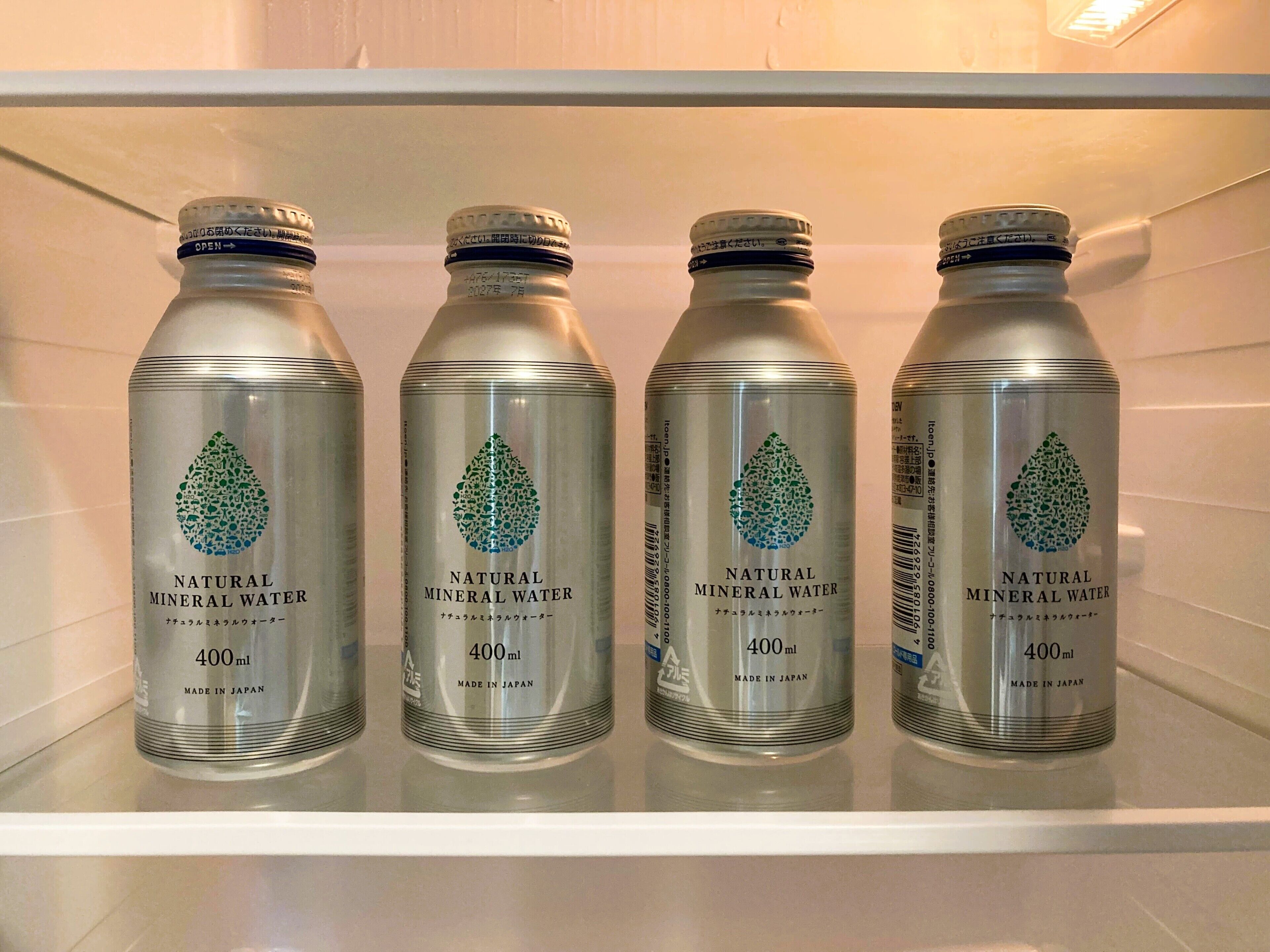 Four bottles of natural mineral water on a shelf.