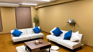 Un salon moderne avec deux canapés blancs, des coussins bleus, une table basse en bois et un tapis blanc.
