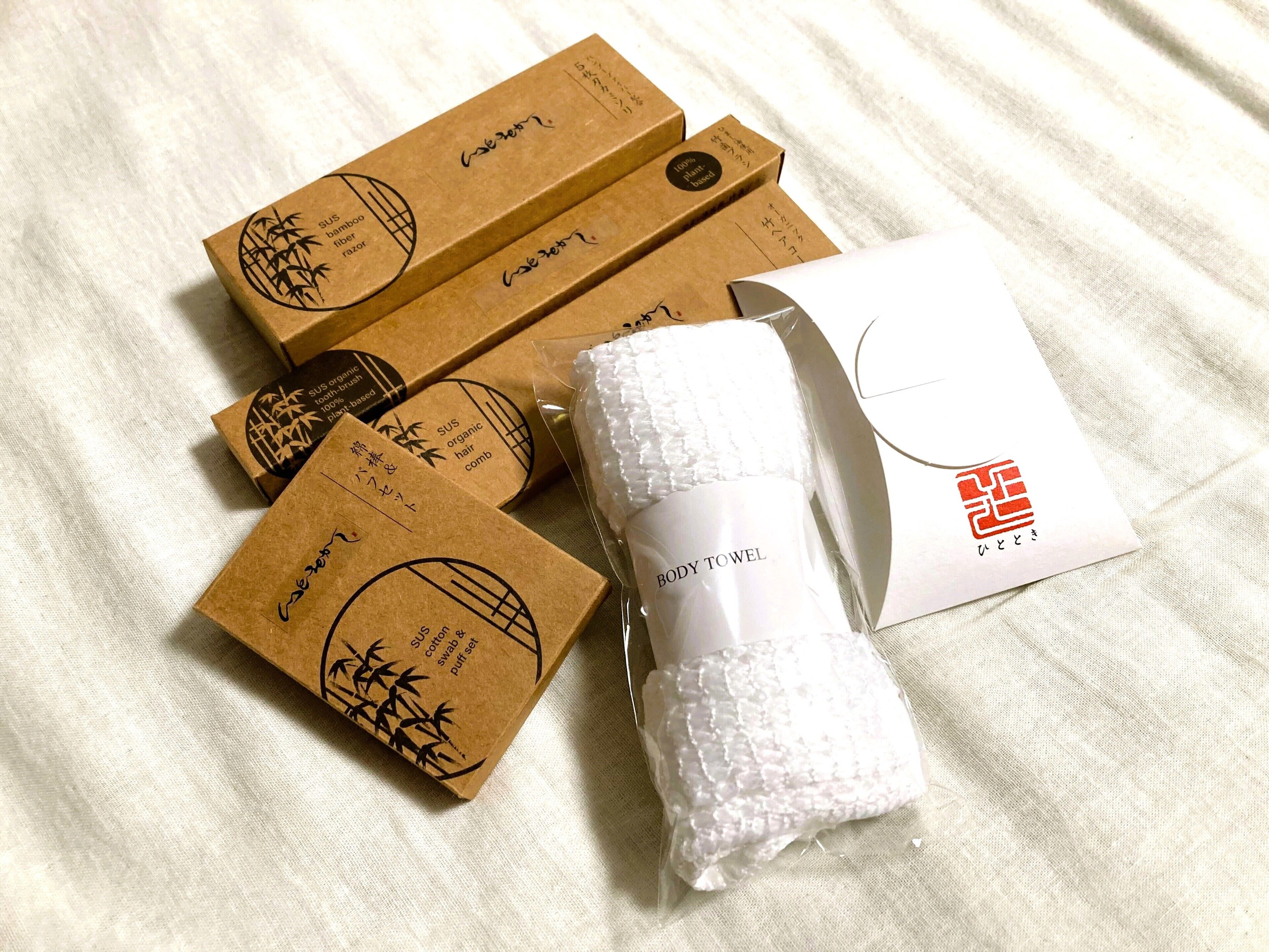 Several cardboard boxes with bamboo fiber labels, a white body towel, and a white package with a red logo.