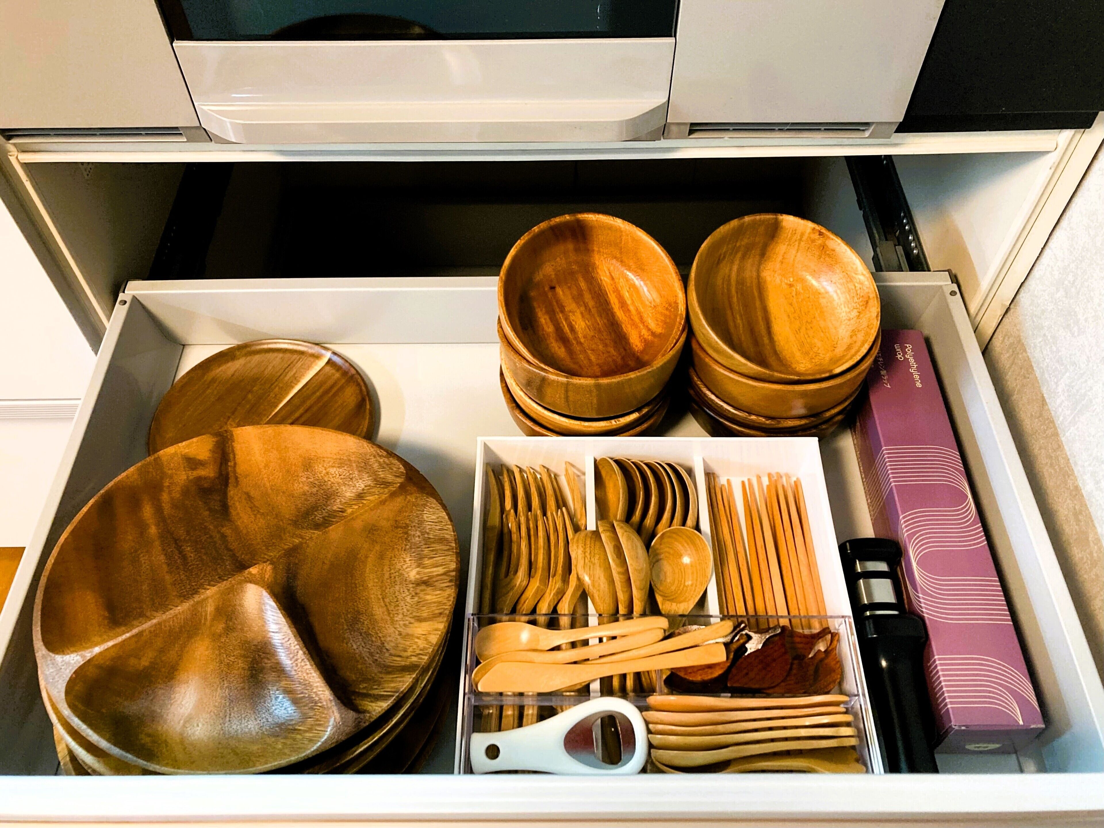 A drawer with wooden bowls, spoons, and a box.