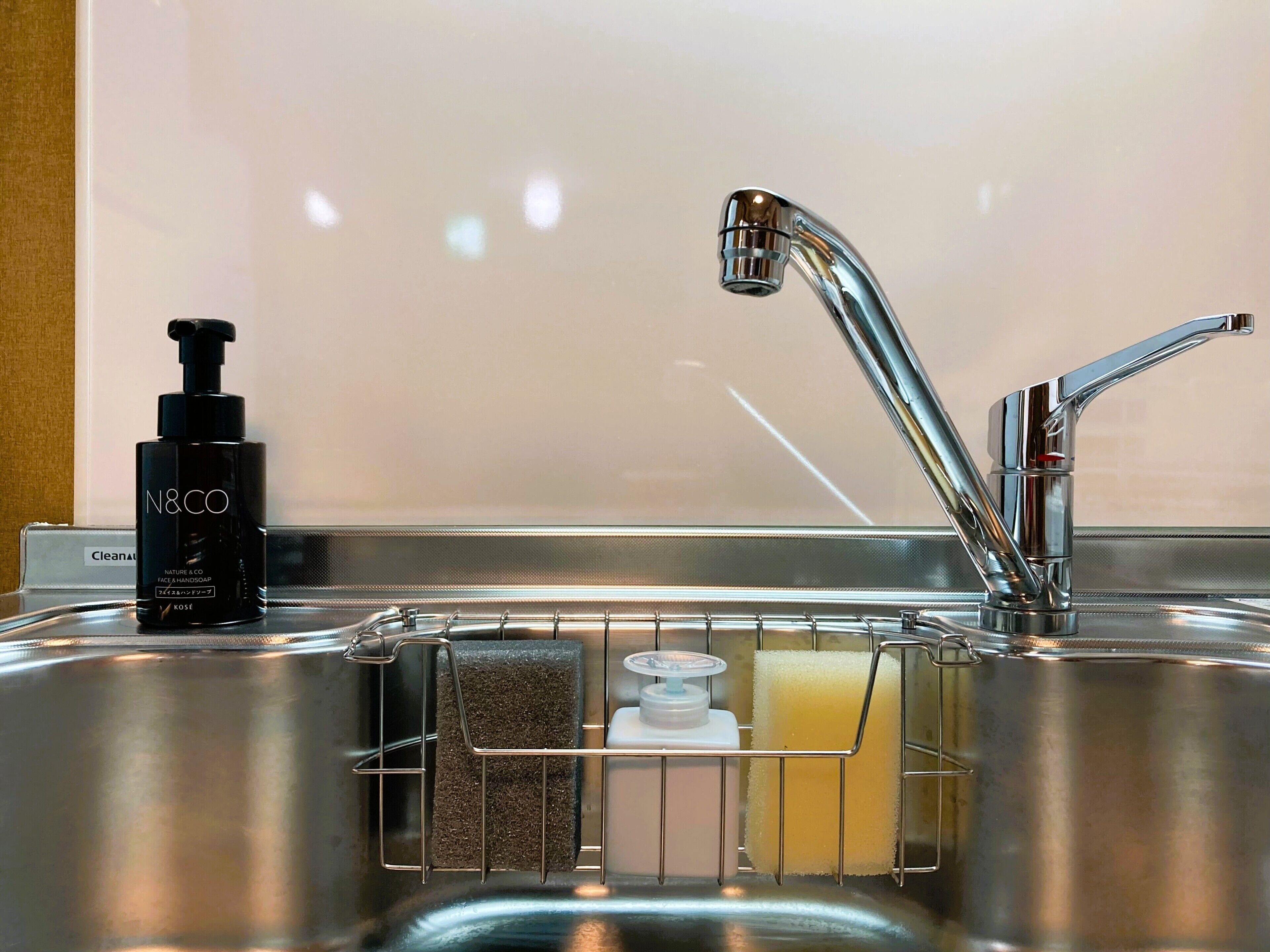 A stainless steel sink with a modern faucet, a soap dispenser, and a sponge rack.