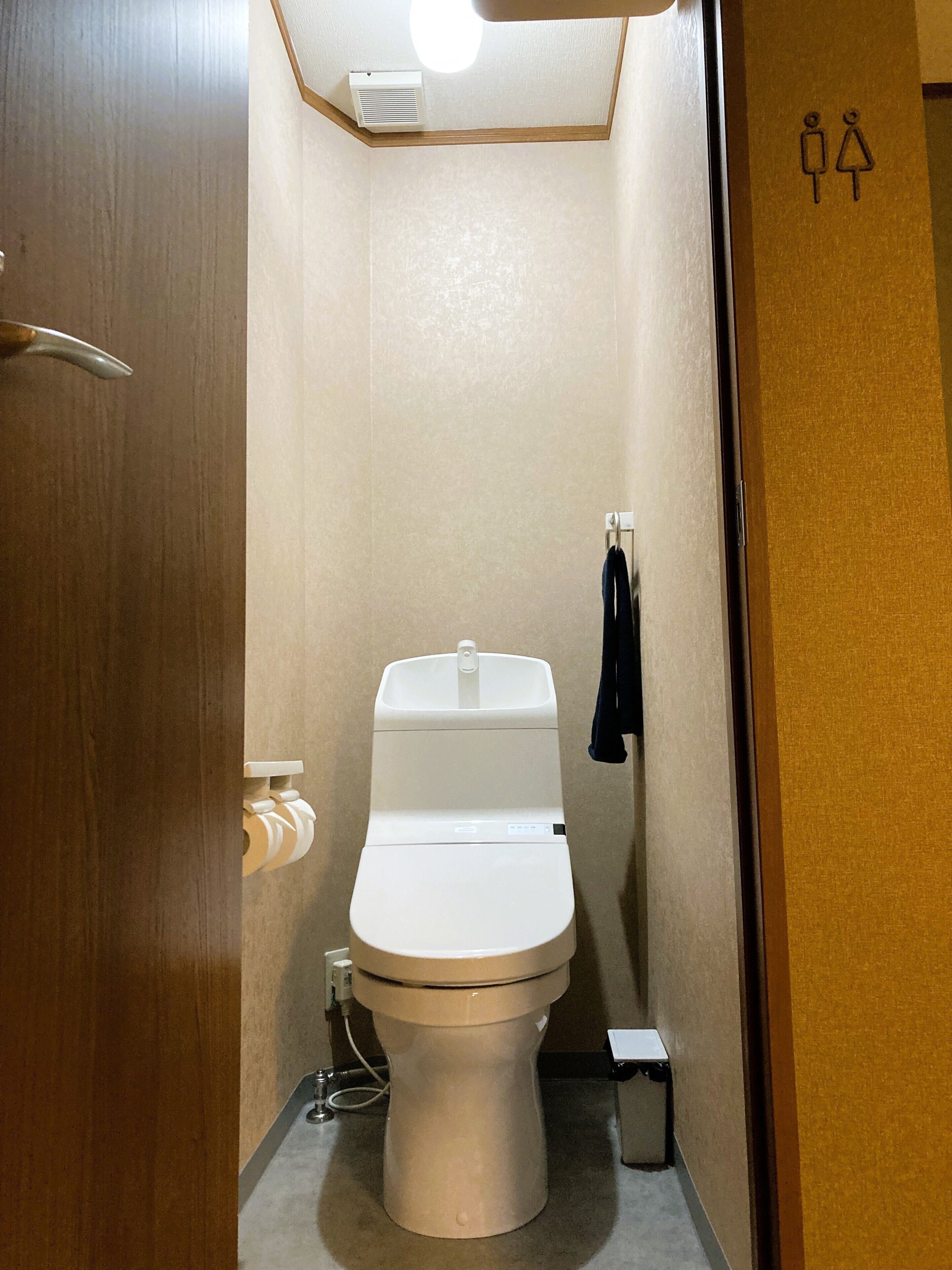 Une salle de bain moderne et compacte, comprenant des toilettes, un petit lavabo et un porte-serviettes.