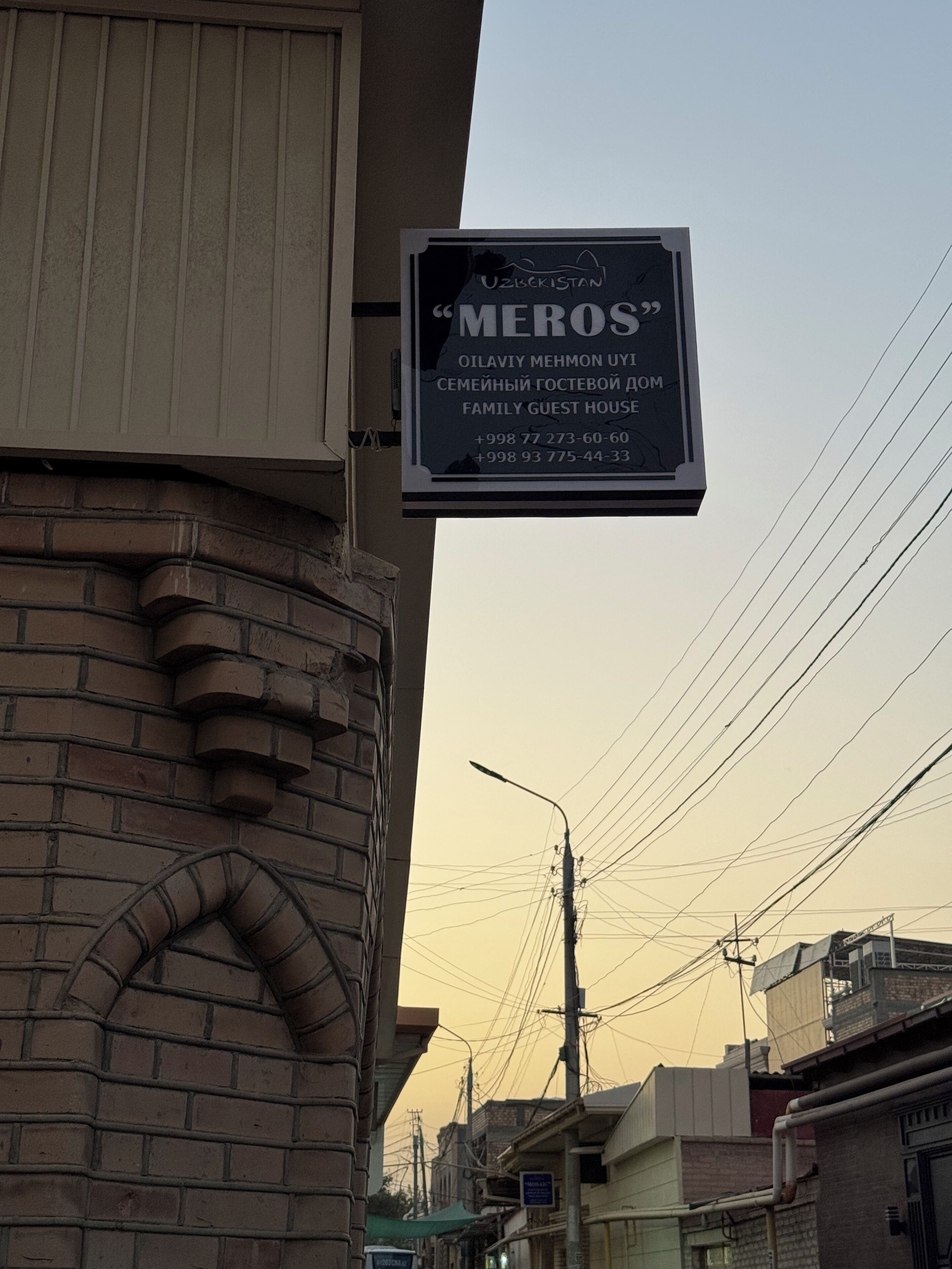 A sign for a family guest house with contact numbers.