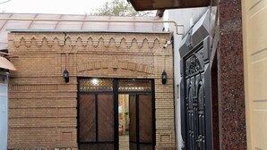 A building entrance with a tiled roof, a brick facade, and a metal gate. - Meros Guest House (Samarkand)