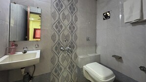A bathroom with a sink, mirror, shower, and toilet. - Hotel Kailash Park (Mumbai)