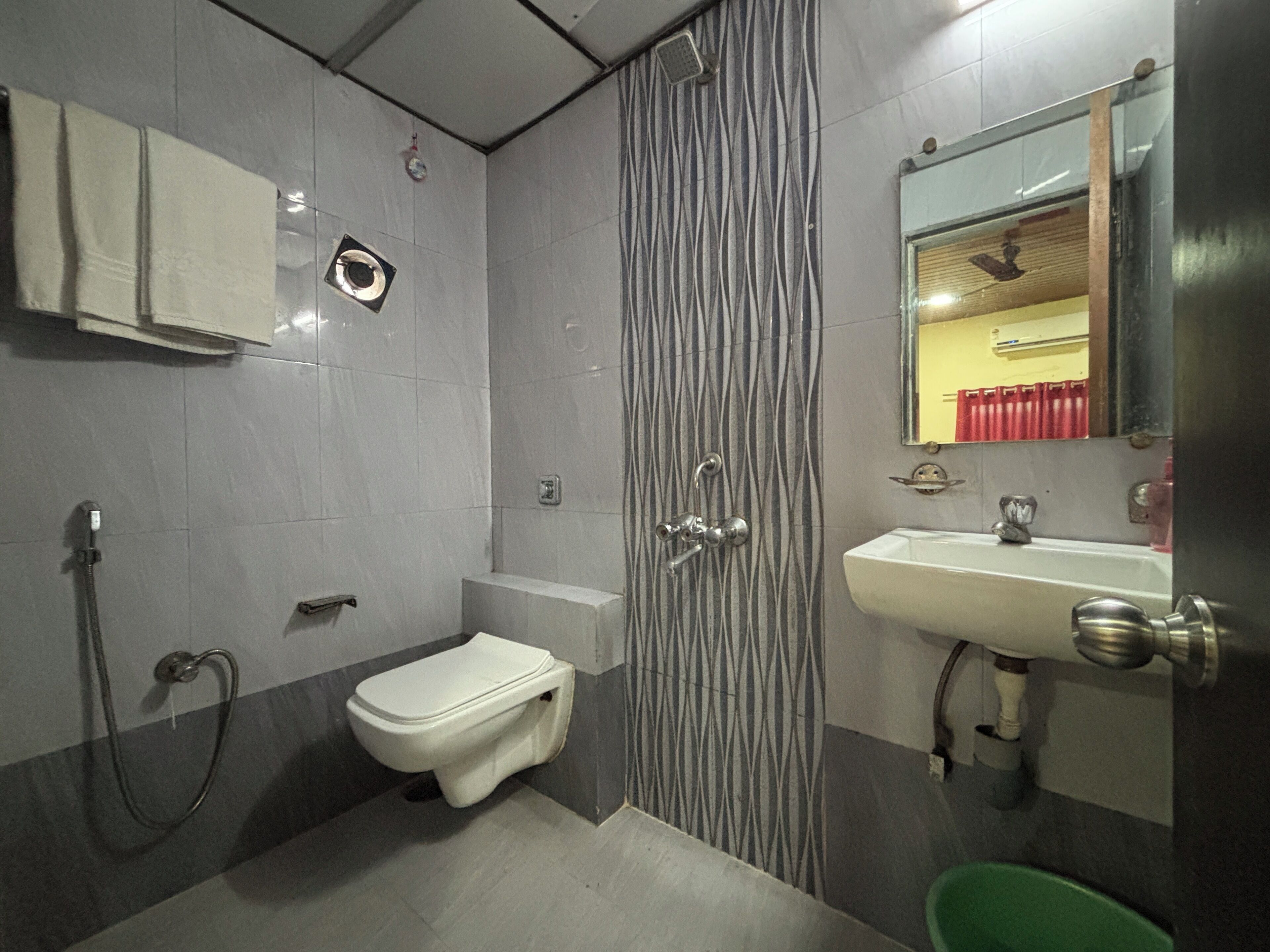 A bathroom with a toilet, shower, sink, and mirror.