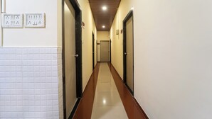 A hallway with a tiled floor, wooden ceiling, and doors on both sides. - Hotel Kailash Park (Mumbai)