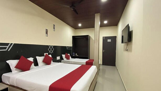 A hotel room with two beds, a TV, and a door. - Hotel Kailash Park (Mumbai)