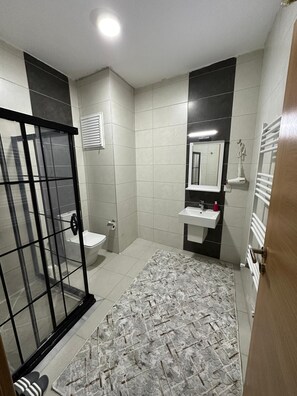 A bathroom with a toilet, sink, and shower area.
