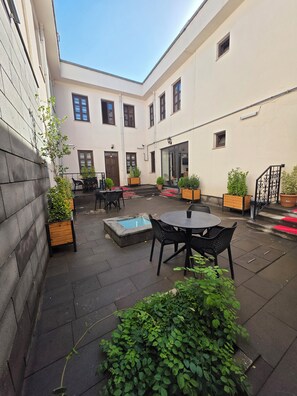 A courtyard with a pool, outdoor seating, and potted plants.