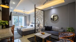 A modern hotel room with a bed, sofa, dining area, and a balcony with a view. - Bedchambers Apart hotel Sec 39 (Gurugram)