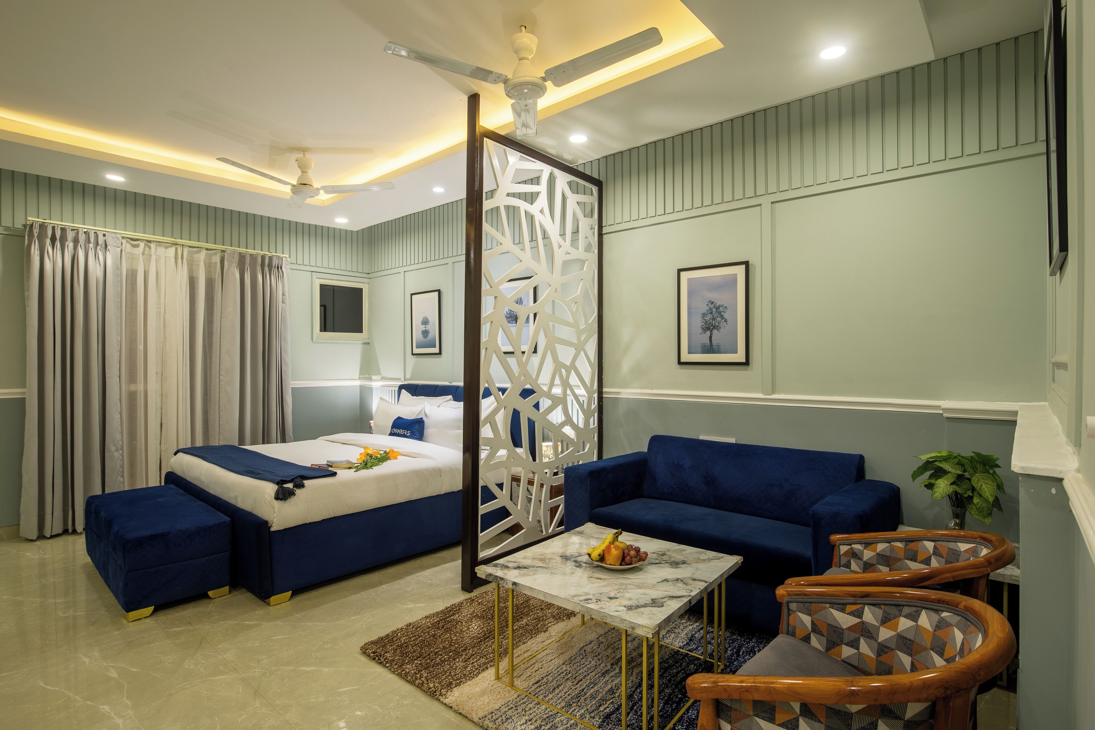 A modern hotel room with a bed, sofa, and a small dining area.