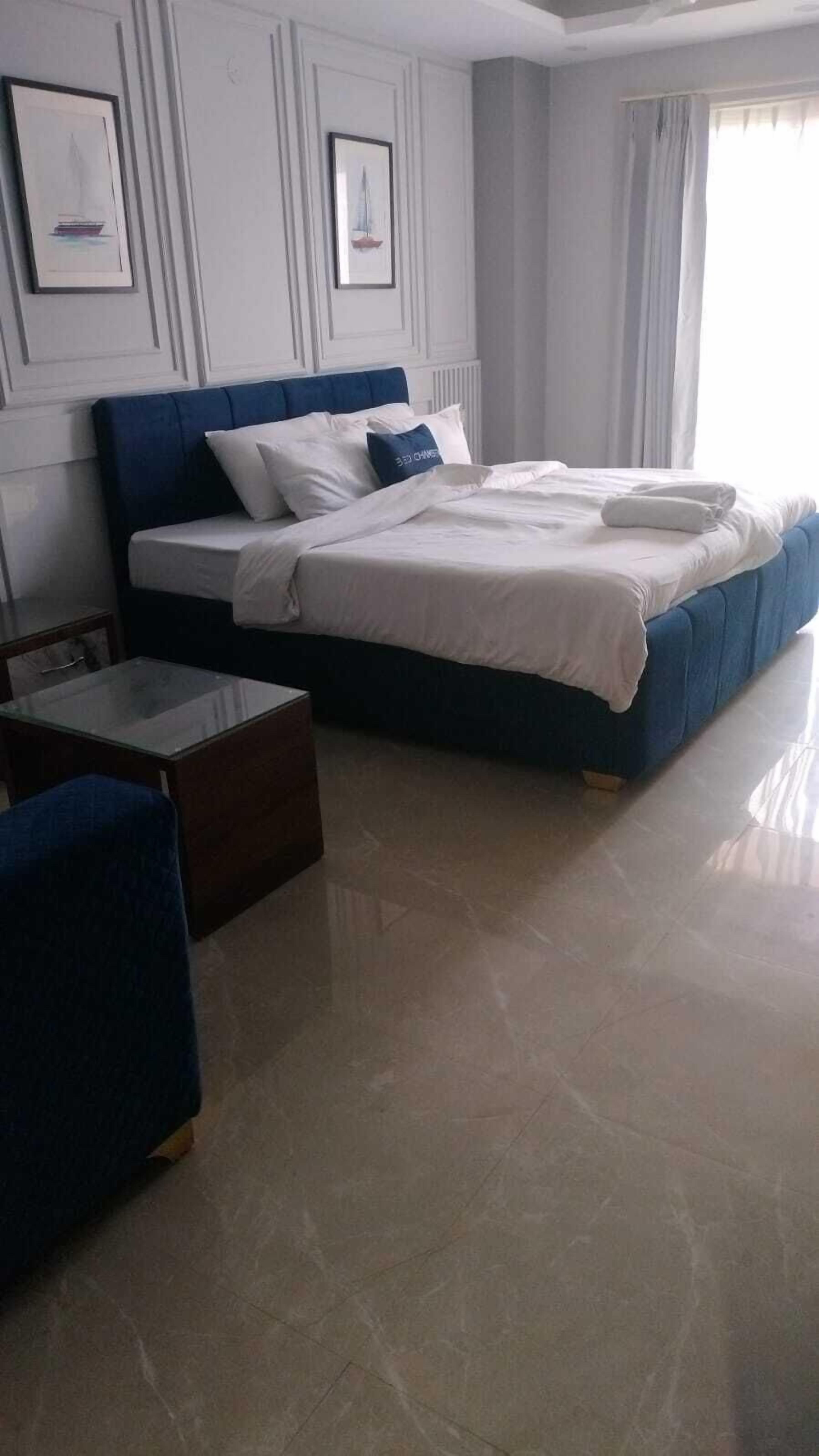 Ein Hotelzimmer mit einem Bett, einem kleinen Tisch, einem Stuhl und einem Fenster mit Vorhängen.