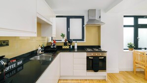 A modern kitchen with a black countertop, white cabinets, a Bosch gas stove, and a window with a view. - Spacious 2BR, 2 Bath with Balcony Sleeps 6 (Greater London)