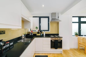 A modern kitchen with a black countertop, white cabinets, a Bosch gas stove, and a window with a view. - Spacious 2BR, 2 Bath with Balcony Sleeps 6 (Greater London)