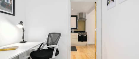 Una habitación moderna y minimalista con escritorio, silla y vista a la cocina.