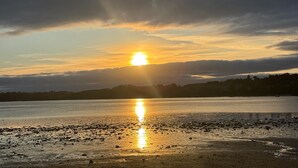 A sunset over a calm body of water with a distant shoreline.