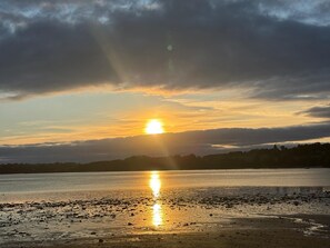 A sunset over a calm body of water with a distant shoreline.