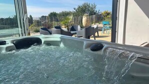 A hot tub with water jets, outdoor seating, and a view of the surrounding area.