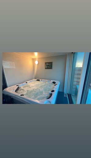 Un bain à remous dans une pièce dotée d’une porte en verre et d’un petit tableau accroché au mur.