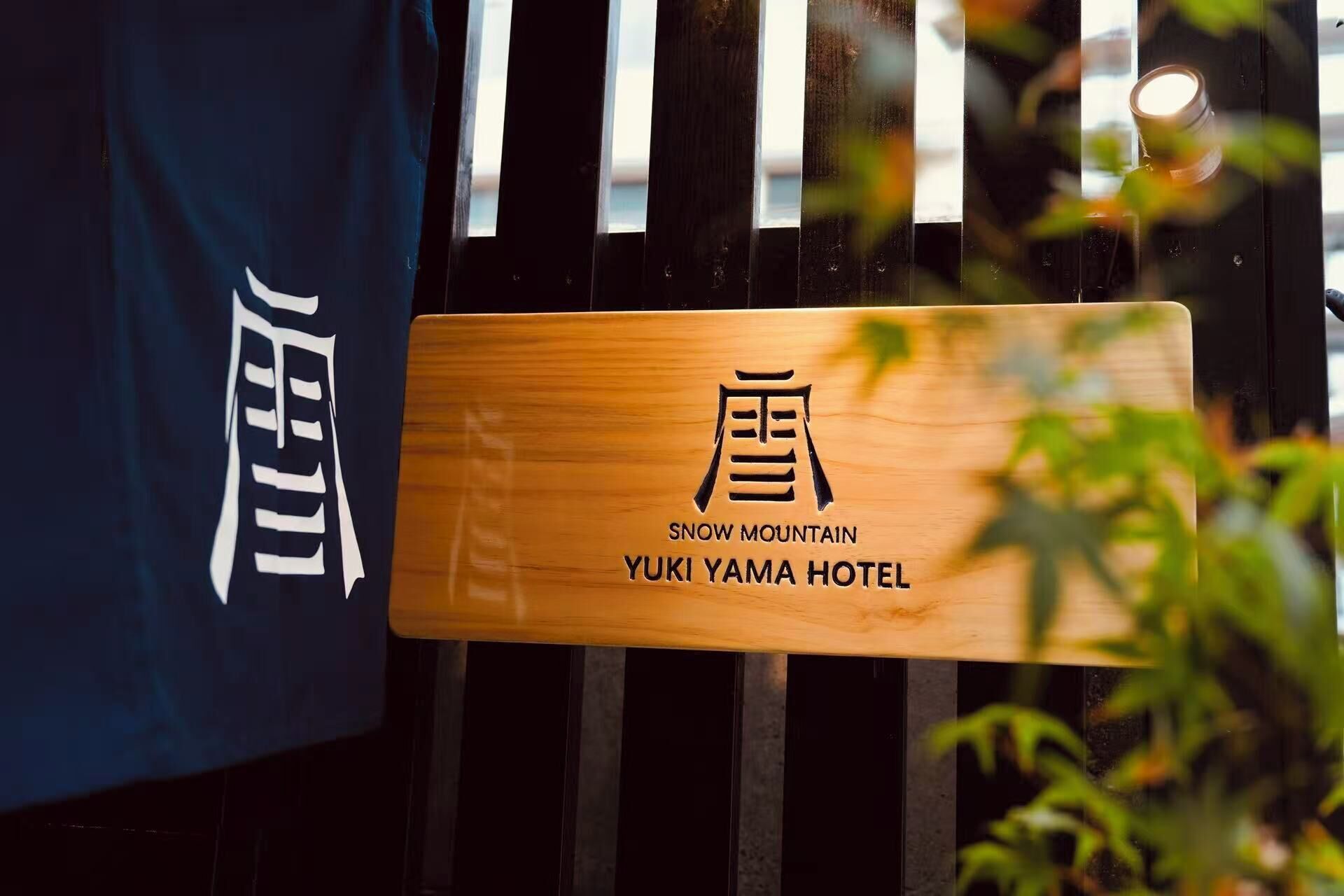A wooden sign with the name 'Snow Mountain Yuki Yama Hotel' and a Japanese character.