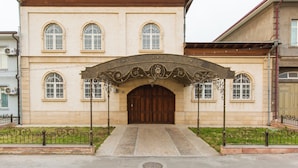 A building with a central arched entrance, multiple arched windows, and a symmetrical facade. - New Friends Mini Hotel (Tashkent)
