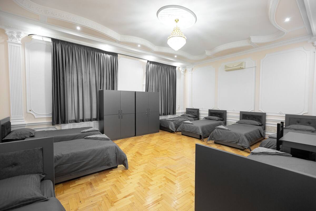 A hotel room with four single beds, a wardrobe, a desk, and a chandelier.
