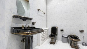 A bathroom with a black and gold sink, a white toilet, and a trash can. - New Friends Mini Hotel (Tashkent)