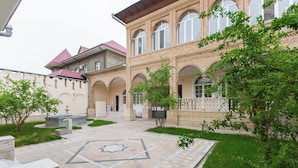 A courtyard with a fountain, a star-shaped tile pattern, and a building with arched windows and a brick facade. - New Friends Mini Hotel (Tashkent)
