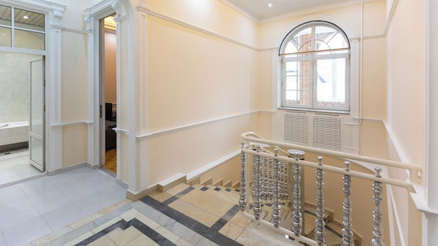 A spacious hallway with a marble floor, a staircase with ornate balustrades, and a large arched window allowing natural light. - New Friends Mini Hotel (Tashkent)