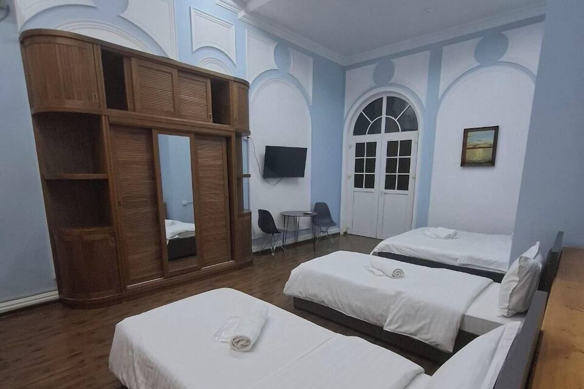 A hotel room with two beds, a wooden wardrobe, a TV, and a door with a window.