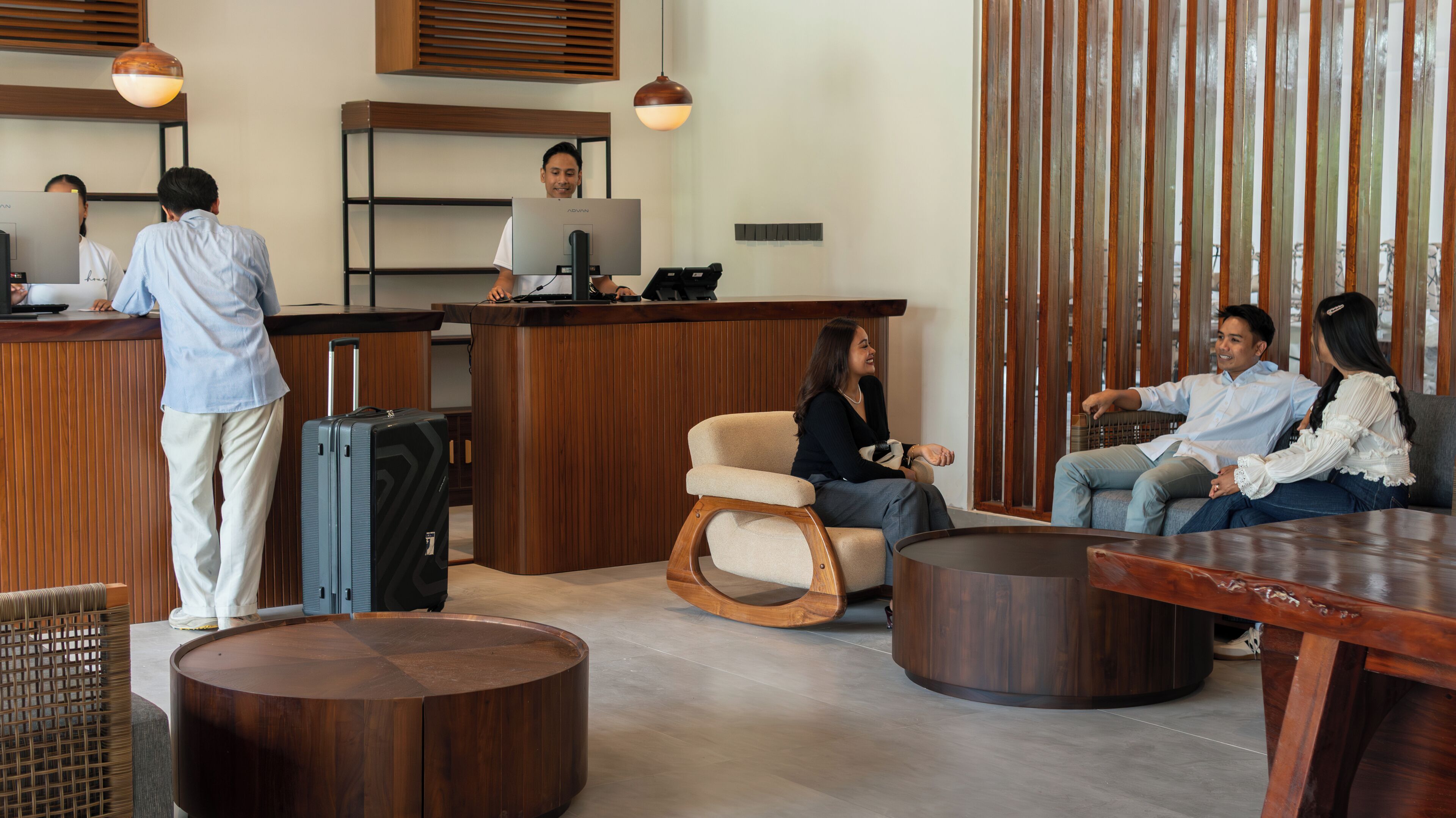 A reception area with a wooden reception desk, a computer, and a seating area with a round wooden table and chairs.