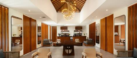 A spacious lobby with a central reception desk, seating area, and a high ceiling with a unique chandelier.