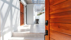 A wooden door leading to a staircase with a view of a patio area.